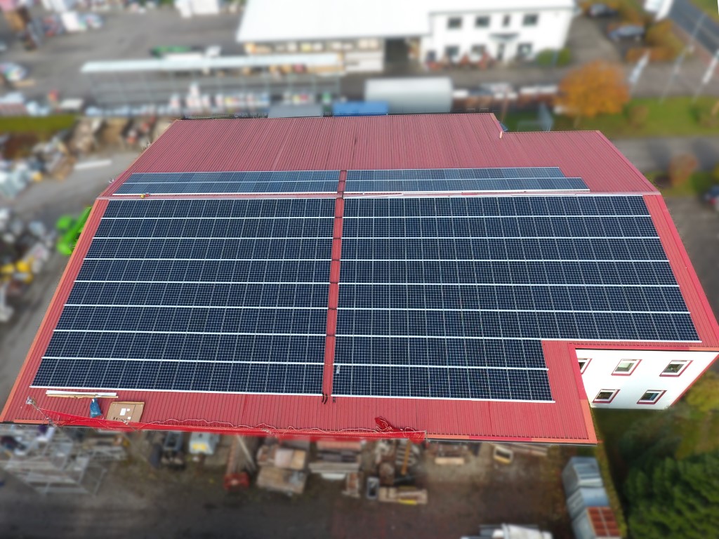 Unternhemen mit rotem Dach in der Installation der Photovoltaikanlage (Mittel)